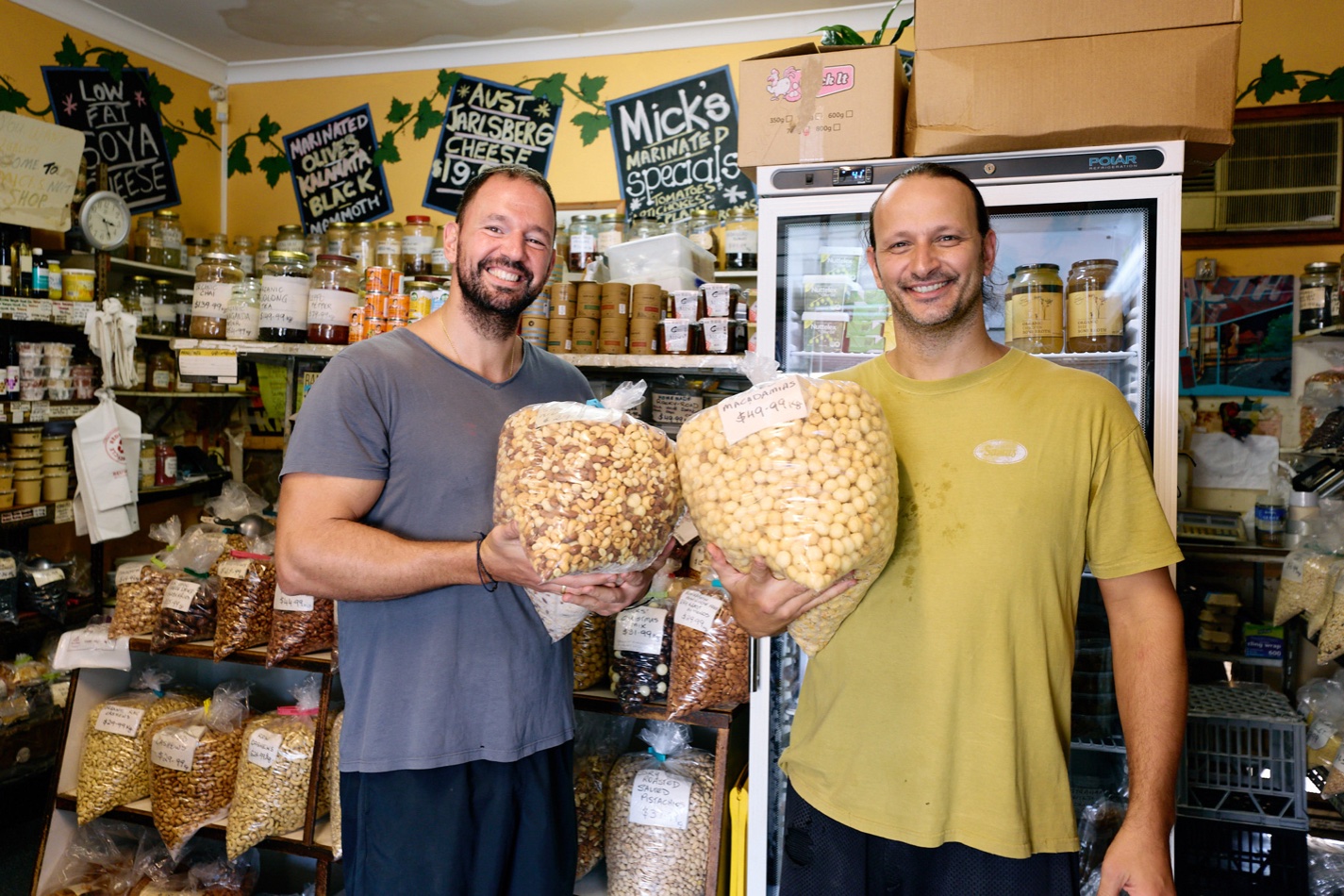 George and Emmanuel Conias, owners of Micks Nuts since 2014, holding bags of nuts inside the West End store.